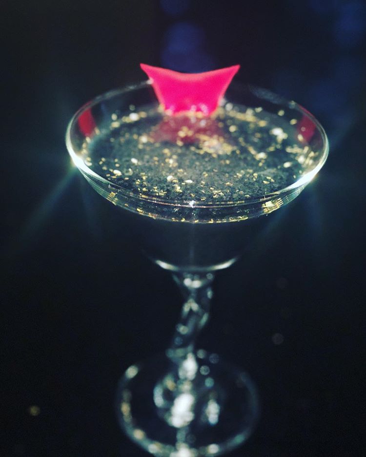 dark colored cocktail with rose petal